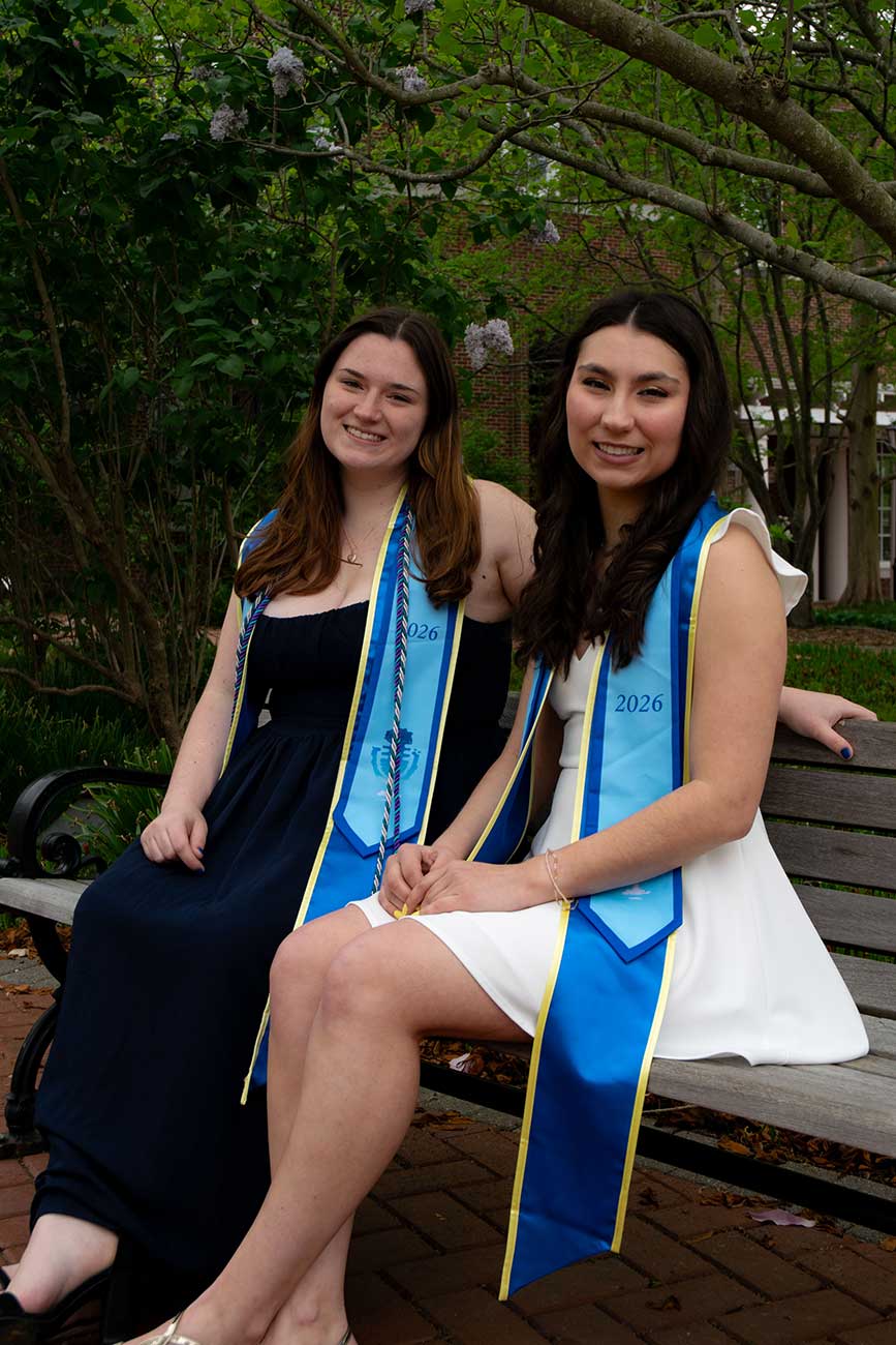 Caitlin and Chase sitting together wearing University of Delaware graduation regalia